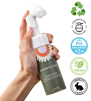 Hand holding Dandylion pet foaming cleanser bottle for dog grooming with eco-friendly and vegan icons