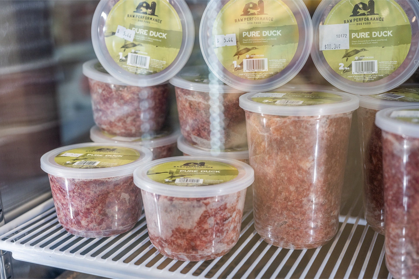 Raw Performance Pure Duck Raw Dog Food in clear containers stacked in a freezer display