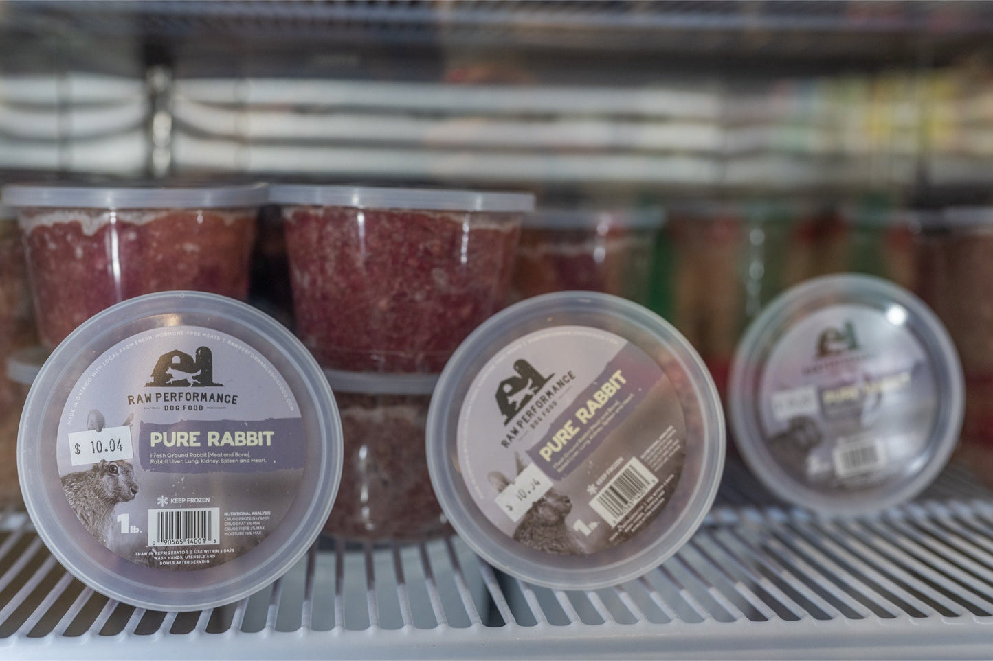 Raw Performance pure rabbit raw dog food in containers displayed in a freezer for pet owners
