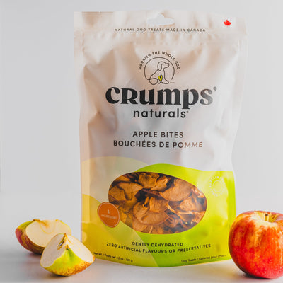 Crumps Natural apple bites dehydrated dog treats in resealable bag with fresh apples nearby