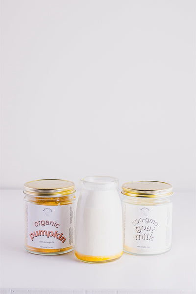 Holisticanine non-gmo goat milk supplement jar next to organic pumpkin jar and a glass bottle of milk