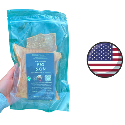 Real Dog Box pig skin dog treats in resealable blue packaging held in hand with American flag icon